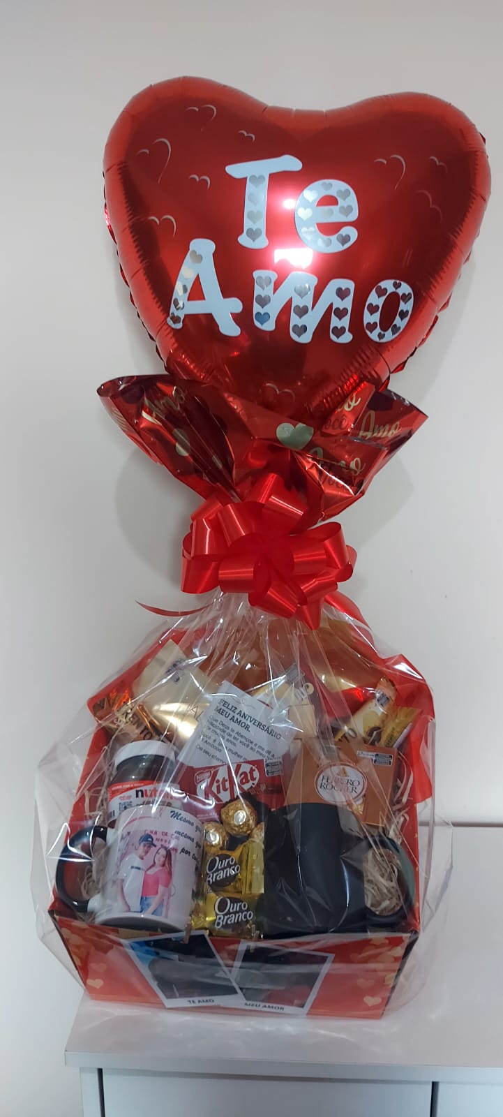 Cesta para presente, contém um balãoo no topo com a escrita eu te amo, canecas, cholocates entre outros itens.